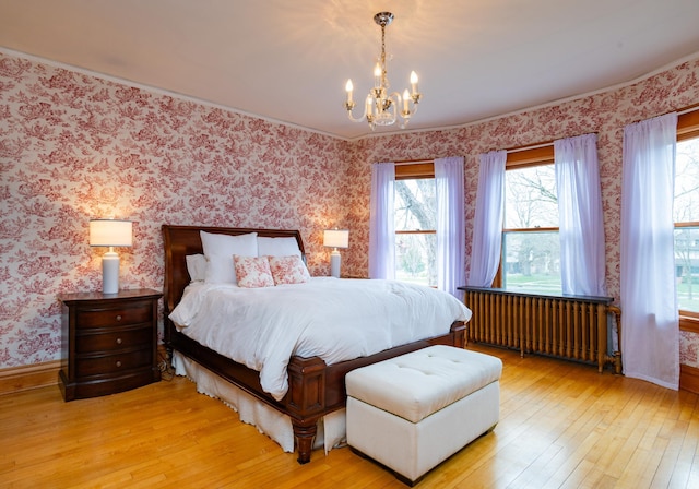 bedroom featuring radiator, light wood-style floors, a chandelier, baseboards, and wallpapered walls