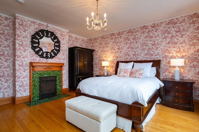 bedroom with wallpapered walls, a fireplace, light wood finished floors, and crown molding