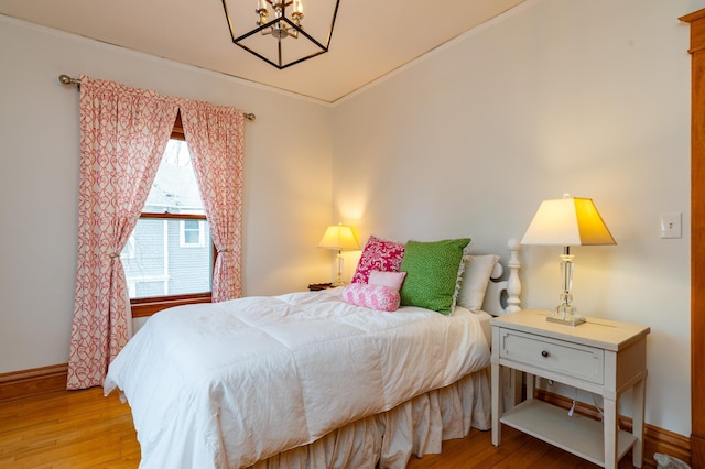 bedroom featuring light wood-style flooring, baseboards, and a notable chandelier