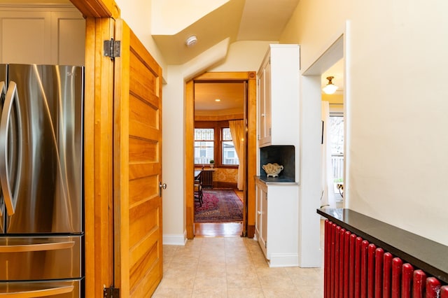 corridor with light tile patterned floors and radiator heating unit