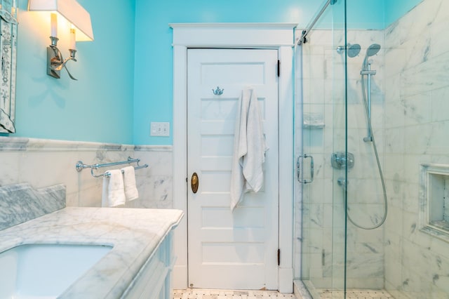 full bath with wainscoting, a shower stall, tile walls, and vanity