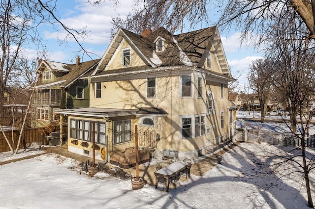 snow covered house featuring gravel driveway and fence