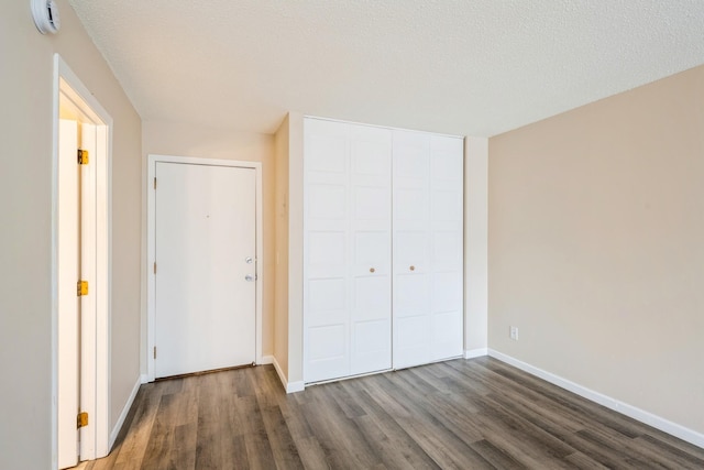 unfurnished bedroom with a closet, baseboards, wood finished floors, and a textured ceiling