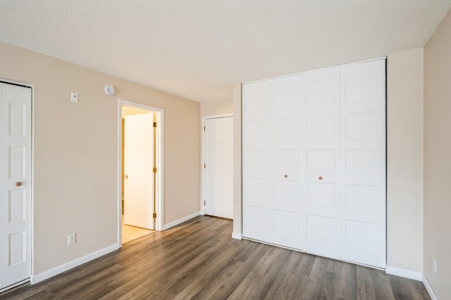 unfurnished bedroom with a closet, baseboards, and dark wood finished floors