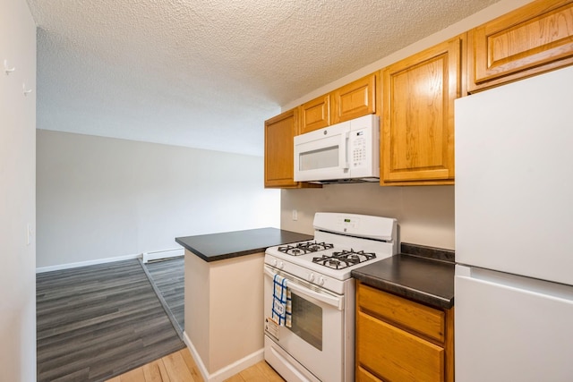 kitchen with dark countertops, white appliances, a textured ceiling, baseboard heating, and dark wood-type flooring