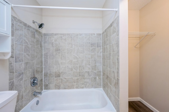 bathroom featuring toilet, shower / bath combination, wood finished floors, and baseboards