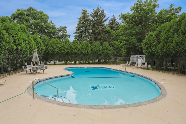 community pool with a patio area and fence