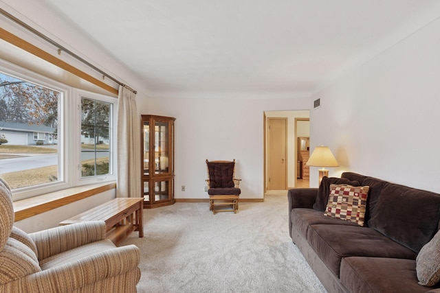 living room with visible vents, light colored carpet, and baseboards