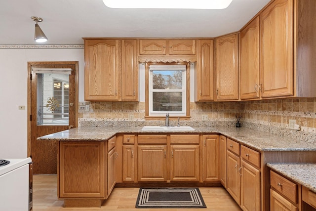 kitchen with a wealth of natural light, light stone countertops, backsplash, and a sink