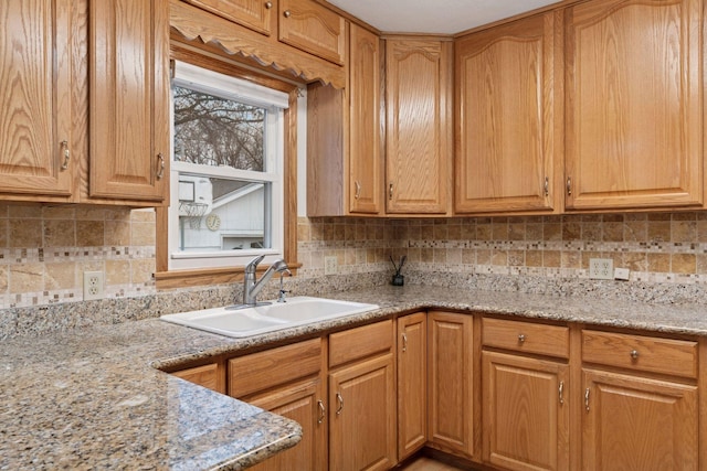 kitchen with a sink, light stone counters, and tasteful backsplash