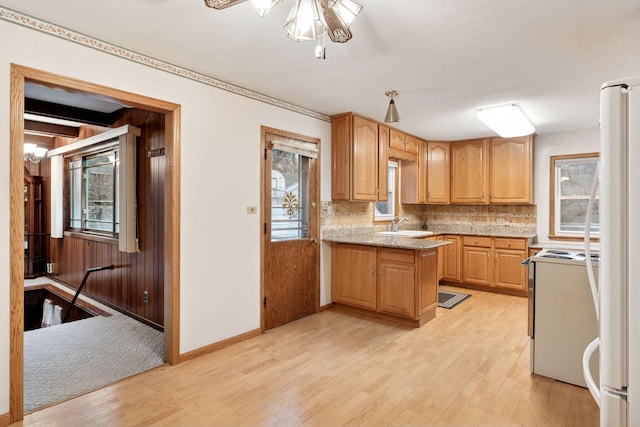 kitchen with white appliances, tasteful backsplash, a peninsula, and light wood finished floors