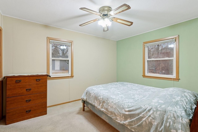 bedroom with a ceiling fan, multiple windows, light colored carpet, and baseboards