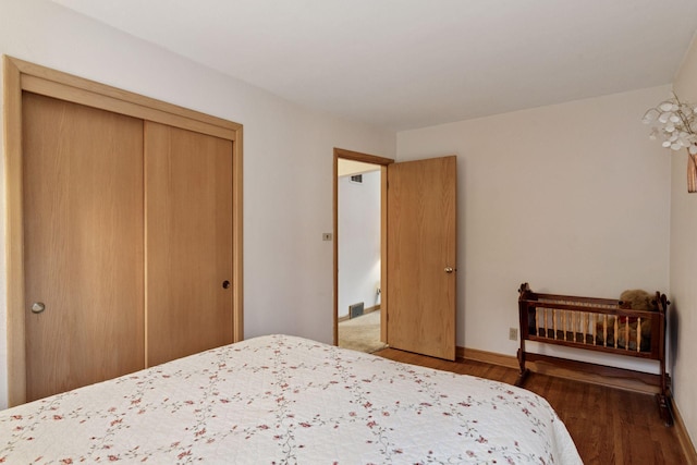 bedroom featuring a closet, baseboards, visible vents, and wood finished floors