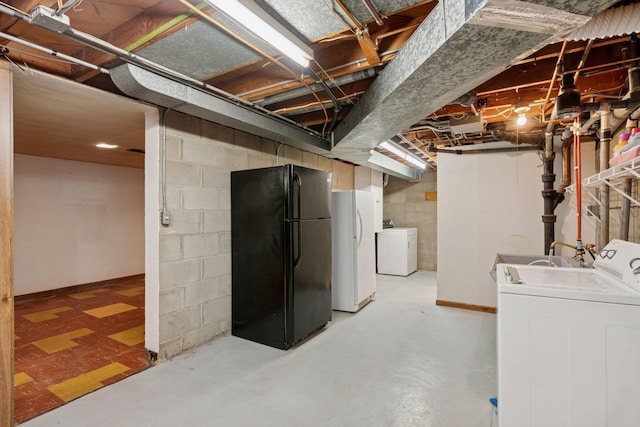 unfinished below grade area featuring washer and clothes dryer, freestanding refrigerator, and a sink