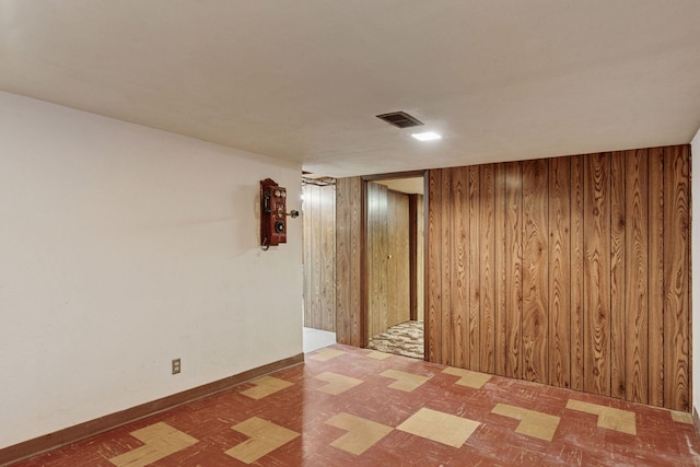 spare room with tile patterned floors, wooden walls, and visible vents