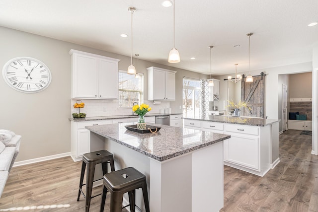 kitchen with white cabinets, a kitchen island, light wood-type flooring, and dishwasher