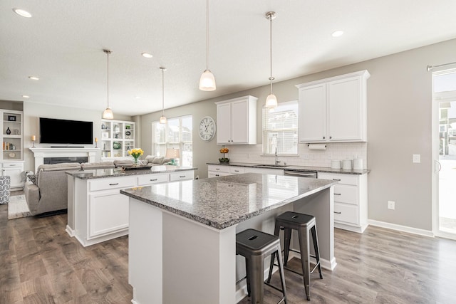 kitchen featuring a sink, a kitchen island, wood finished floors, and open floor plan