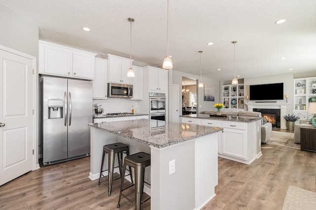 kitchen with open floor plan, light wood finished floors, a kitchen island, and stainless steel appliances