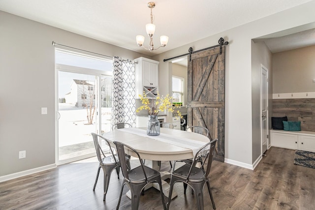 dining room with baseboards, dark wood-style flooring, and a barn door