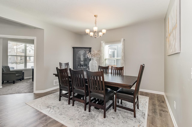 dining space featuring baseboards, wood finished floors, and a notable chandelier