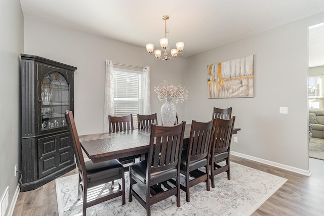 dining room featuring baseboards, light wood-type flooring, and a notable chandelier