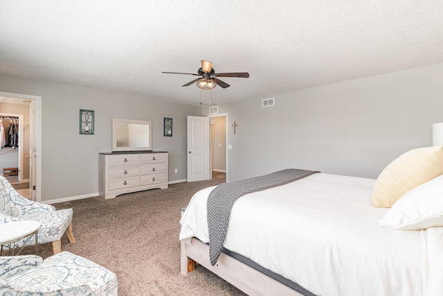 carpeted bedroom featuring ceiling fan, a walk in closet, baseboards, visible vents, and a closet