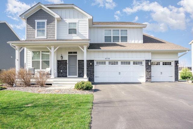 traditional-style home with a shingled roof, covered porch, board and batten siding, and aphalt driveway