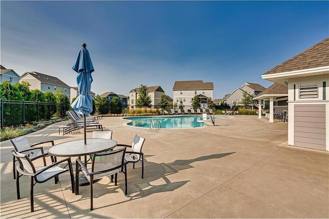 community pool with fence, a residential view, and a patio area