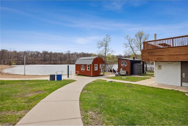 view of yard with a storage unit, an outbuilding, and a deck with water view