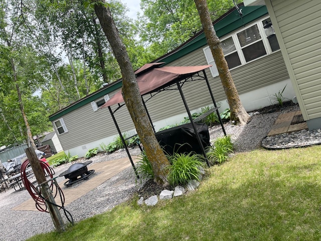 6631 Rocky Point Rd NW, Lakewood Twp, MN 56673 - view of side of home with an outdoor fire pit, a gazebo, a lawn, and a patio area