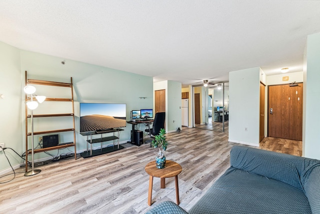 living room featuring light wood-style floors, baseboards, and a ceiling fan