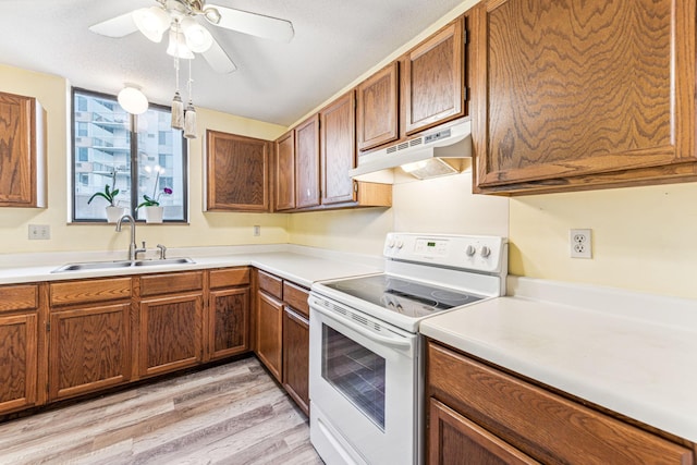 kitchen with light countertops, white electric range, brown cabinetry, a sink, and under cabinet range hood