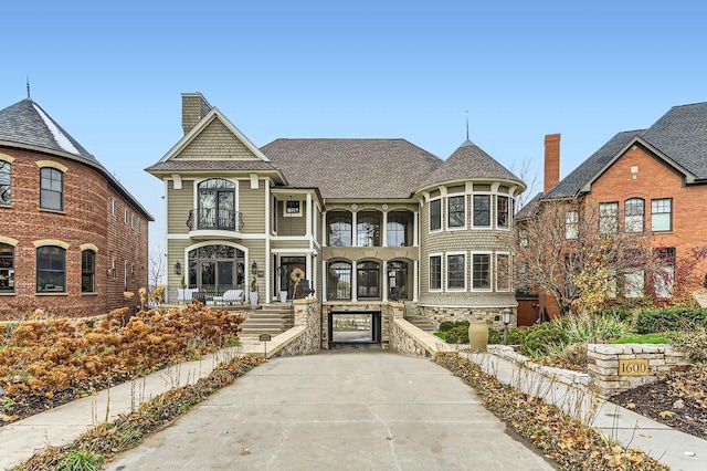 victorian home featuring a chimney and a balcony