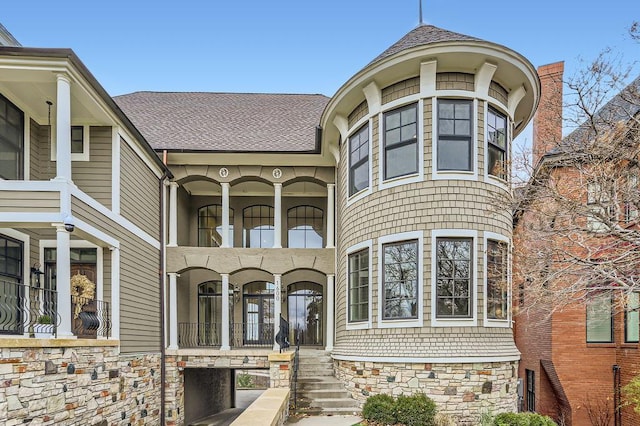 view of front of house featuring a balcony and a shingled roof