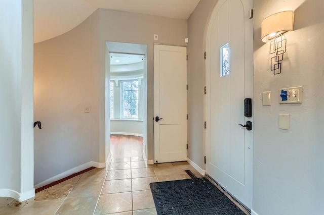 foyer featuring light tile patterned floors and baseboards