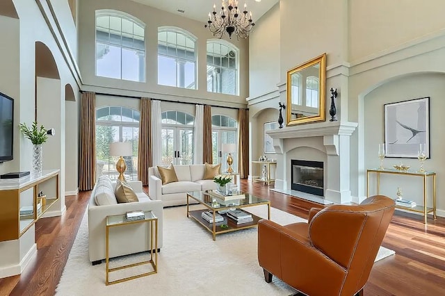 living room featuring a chandelier, a glass covered fireplace, wood finished floors, and baseboards