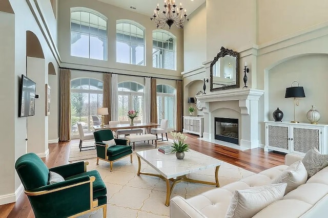 living room featuring wood finished floors, a fireplace with flush hearth, and a notable chandelier