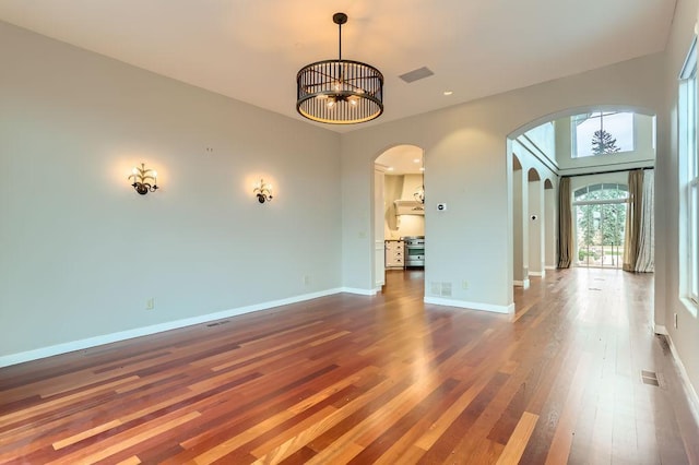 interior space with arched walkways, visible vents, baseboards, and wood finished floors