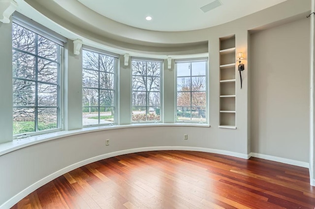 spare room featuring visible vents, baseboards, hardwood / wood-style floors, built in shelves, and recessed lighting