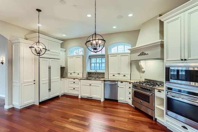 kitchen with appliances with stainless steel finishes, custom range hood, a notable chandelier, and dark wood-style floors