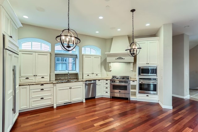 kitchen with an inviting chandelier, custom range hood, a sink, and built in appliances