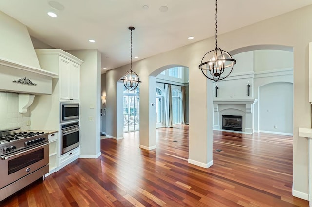 kitchen with custom exhaust hood, an inviting chandelier, appliances with stainless steel finishes, and decorative backsplash