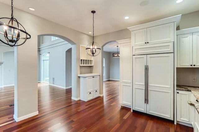 kitchen with dark wood-style floors, arched walkways, a notable chandelier, recessed lighting, and paneled refrigerator