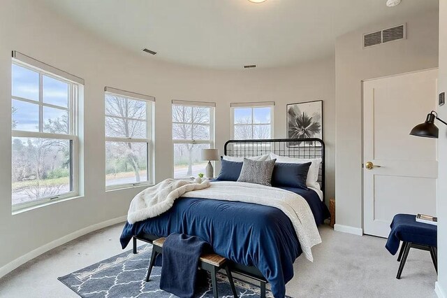 bedroom with visible vents, light carpet, and baseboards