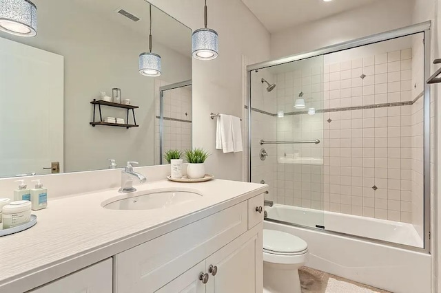 full bathroom featuring enclosed tub / shower combo, visible vents, vanity, and toilet