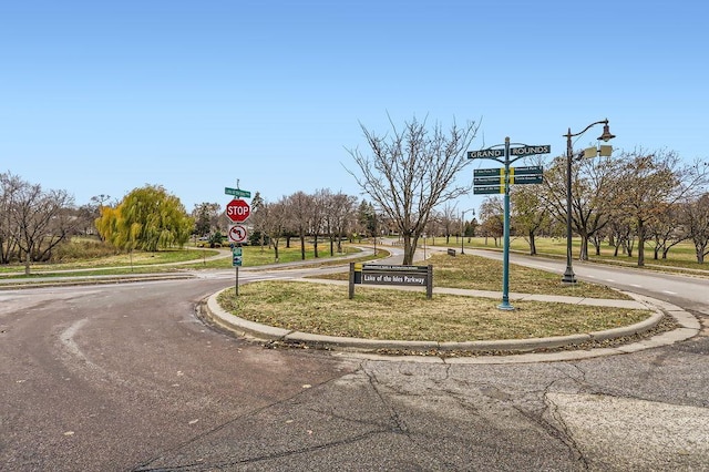 view of road featuring traffic signs, street lights, and curbs