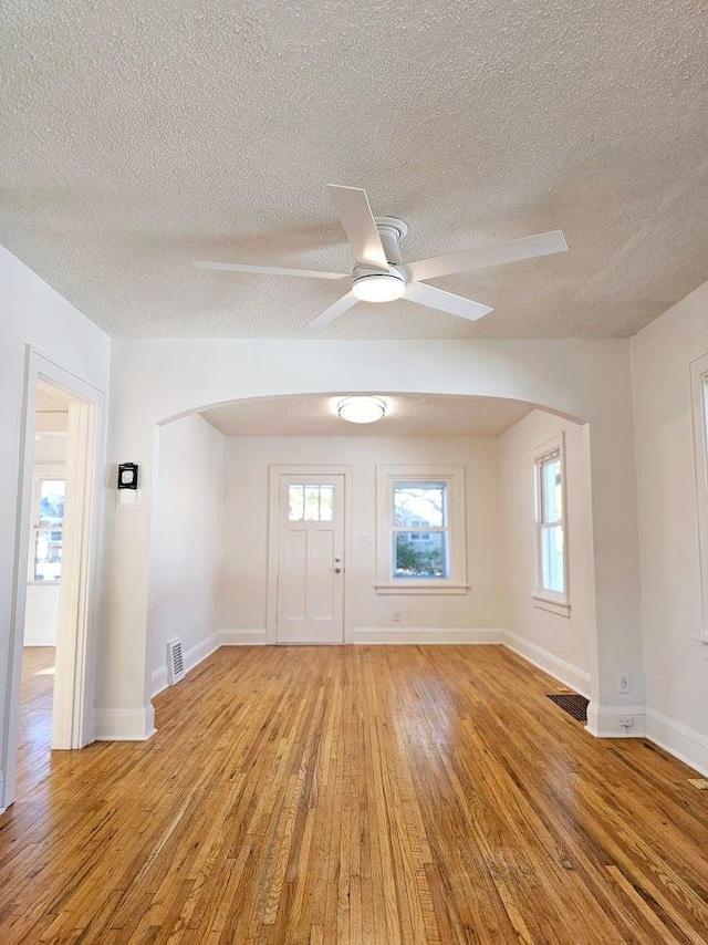 foyer with ceiling fan, a textured ceiling, light wood-style flooring, visible vents, and baseboards