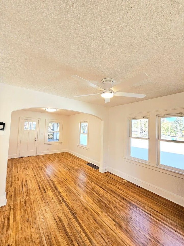 unfurnished room featuring a ceiling fan, light wood-style flooring, visible vents, and baseboards