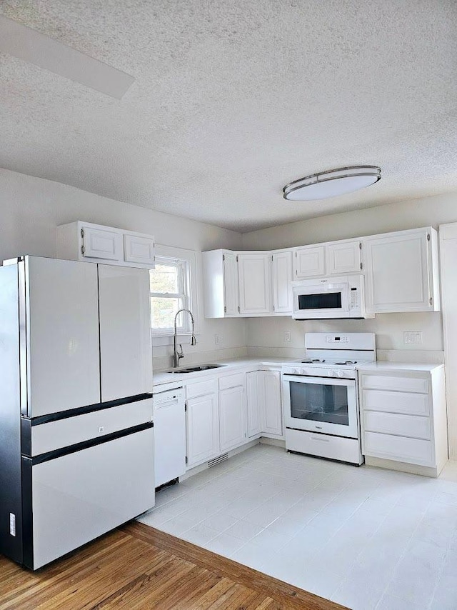 kitchen with white appliances, white cabinets, and a sink