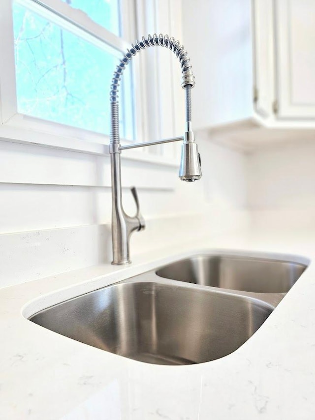 details featuring light countertops, a sink, and white cabinets